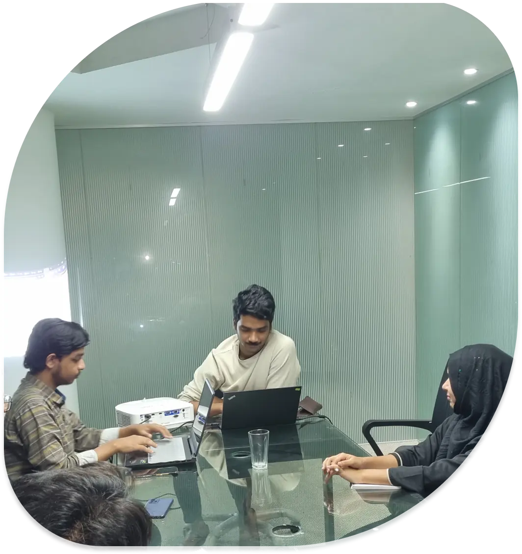 Four people sitting around a table with laptops during a team meeting